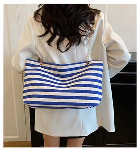 Detail of blue and white striped tote bag with elegant gold metal chain shoulder strap