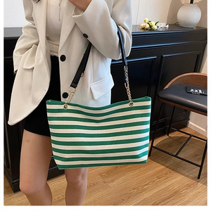 Detail of green and white striped knit tote bag with golden chain and black straps