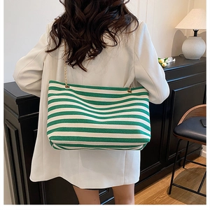 Close-up of a green and white striped tote bag with a golden chain on a model shoulder