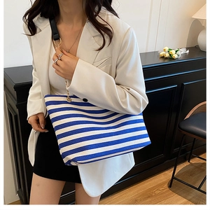 Detail view of blue and white striped tote bag with gold chain and leather strap
