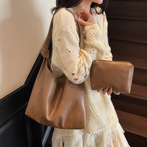 Brown leather knot shoulder tote bag with matching pouch on indoor wooden stairs