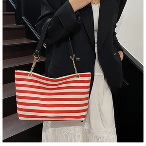 Detail of red and white striped tote bag with black leather and gold chain handles