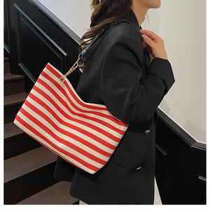 Detail of red and white striped canvas tote bag with black leather and chain strap