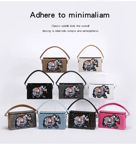 Multiple colors of vintage elephant embroidered box bags displayed on clear stands