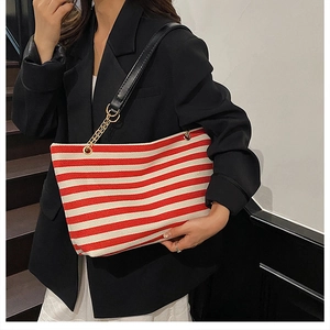 Close-up of red and white striped tote bag with golden chain and black leather strap