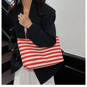 Detail of red and white striped canvas tote bag with elegant gold chain shoulder strap