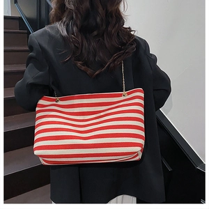 Detail of red and white striped canvas tote bag with gold chain strap on shoulder