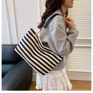 Close-up of black and white striped tote bag with elegant metal chain shoulder strap