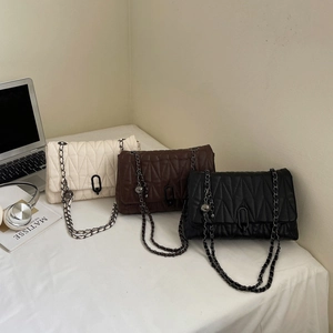 Chic quilted rhombic chain bags in off-white, brown, and black colors on an office desk