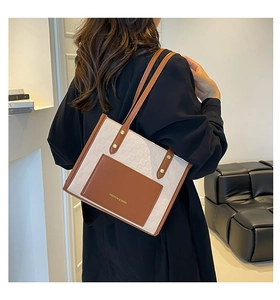 Détail d'un sac cabas minimaliste avec coutures contrastées et poche en cuir marron
