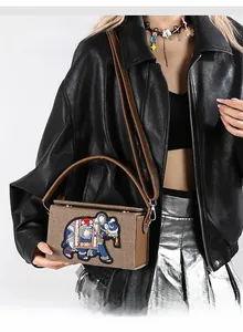Detailed close-up of ethnic elephant embroidery on brown textured crossbody bag