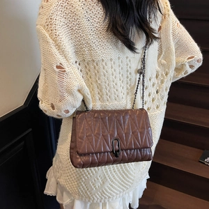 Brown quilted leather shoulder bag with chain strap shown on a model's shoulder