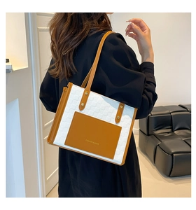 Detail of a chic woven tote bag with brown leather pocket and gold rivet accents