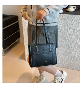 Détail du sac cabas noir à motif damier avec rivets dorés et lettrage imprimé