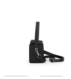 Side view of black structured elephant box bag with top handle and crossbody strap