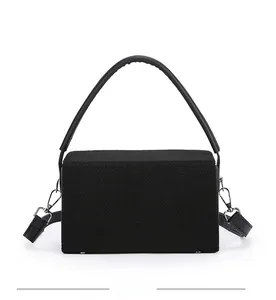 Detailed view of the back of a black embroidered box bag showing fabric texture and base studs