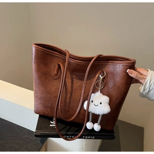 Detailed macro view of retro brown faux leather tote bag texture with plush cloud charm