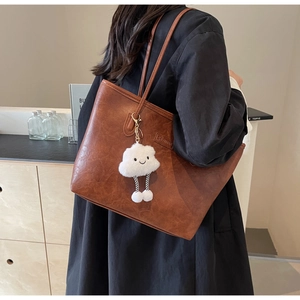 Brown vintage large tote bag with plush cloud charm shown on shoulder in daily setting