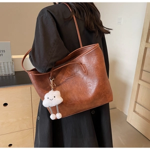 Brown vintage leather tote bag with white cloud plush pendant and brand embossing