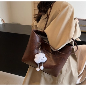 Detail of vintage brown leather tote bag with white cloud charm and shoulder strap