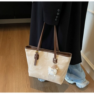 Dettaglio della borsa tote in camoscio beige con manici marroni e ciondolo in peluche