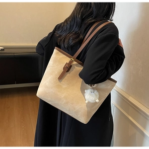 Dettaglio della borsa tote in pelle scamosciata beige con finiture marroni e ciondolo