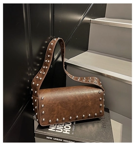 Detail of vintage brown shoulder bag with silver rivets on textured faux leather