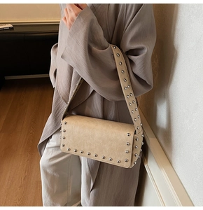 Detail of beige shoulder bag with silver studs and premium leather texture on wide strap