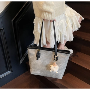 Dettaglio della borsa tote grigia marmorizzata con manici neri e ciondolo in peluche bianco