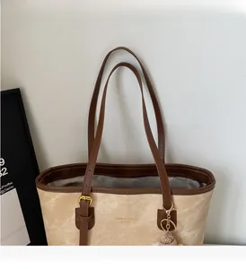 Detail of canvas tote bag with brown leather trim and golden metal adjustment buckle