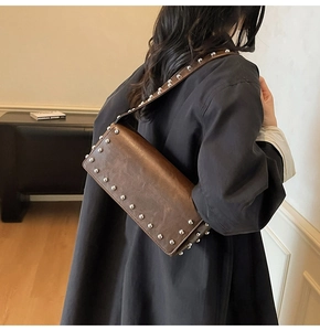 Detail view of vintage brown leather underarm bag with decorative silver rivets and studs