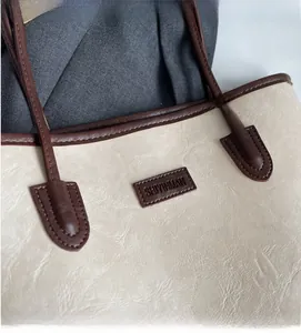 Close-up of contrast stitching and pebble texture on retro tote bag with brand label