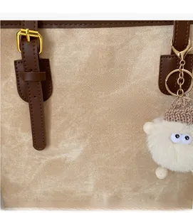 Detailed macro view of the tote bag fabric texture, golden hardware and plush charm