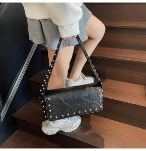 Detail of black rectangular shoulder bag with silver studs and crinkled texture