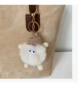 Detail of cute plush charm with brown knit hat and spring clasp on a tote bag