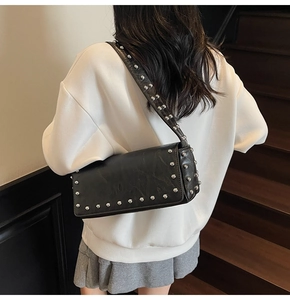 Detail of black baguette shoulder bag featuring silver rivets and retro rock aesthetic