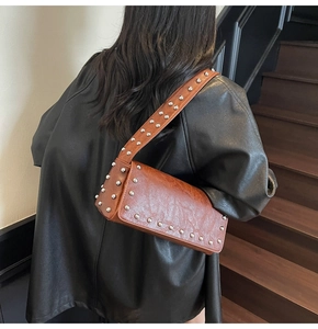 Close-up of brown vintage punk shoulder bag with silver rivets and pleated texture