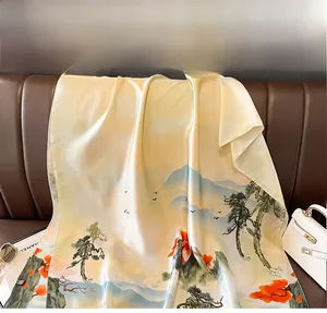 Détail d'une écharpe en soie avec peinture de paysage posée sur un canapé en cuir