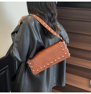 Detailed view of silver metal rivets on brown vintage leather shoulder bag strap