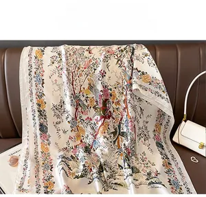Dettaglio di un foulard in seta con stampe di uccelli e fiori su un divano in pelle