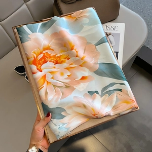 Elegant floral silk scarf with peony print on a golden tray with lifestyle accessories