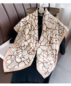 Detail of a large twill silk scarf with beige and brown geometric patterns on black attire