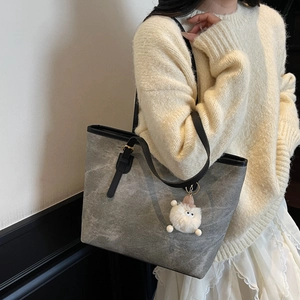 Borsa tote grigia minimalista con trama in pietra vintage e ciondolo in peluche su maglione