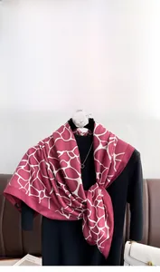 Close-up of geometric red silk scarf with white pattern draped on black turtleneck