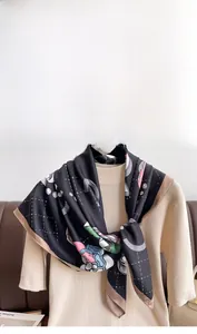 Detail of floral silk scarf with abstract patterns draped on a beige knit top
