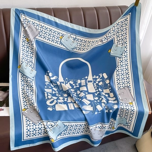 Elegant blue silk square scarf with luxury fashion accessories print draped on a sofa