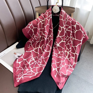 Elegant red twill silk scarf with white geometric giraffe print on a stylish mannequin