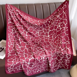Close-up of silk square scarf with dark red giraffe print and smooth satin texture