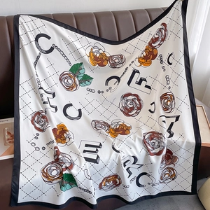 Floral silk square scarf with pearl chains and letters on ivory base over leather sofa