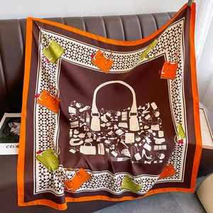 Detail view of square silk scarf featuring handbag and houndstooth patterns on leather sofa